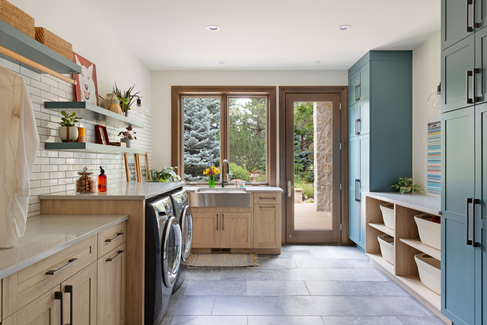 Photo of a mediterranean u-shaped laundry room in Denver with a farmhouse sink, shaker cabinets, light wood cabinets, white walls, a side-by-side washer and dryer, grey floor and grey benchtop.
