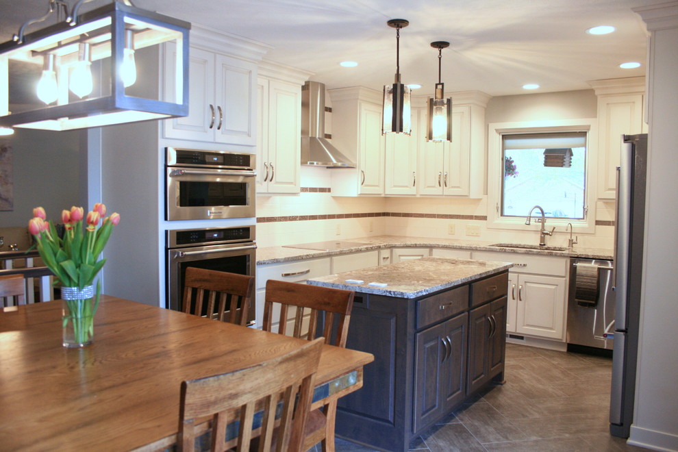 Transitional u-shaped eat-in kitchen photo with an undermount sink, raised-panel cabinets, white cabinets, granite countertops, white backsplash, ceramic backsplash, stainless steel appliances, an island and multicolored countertops