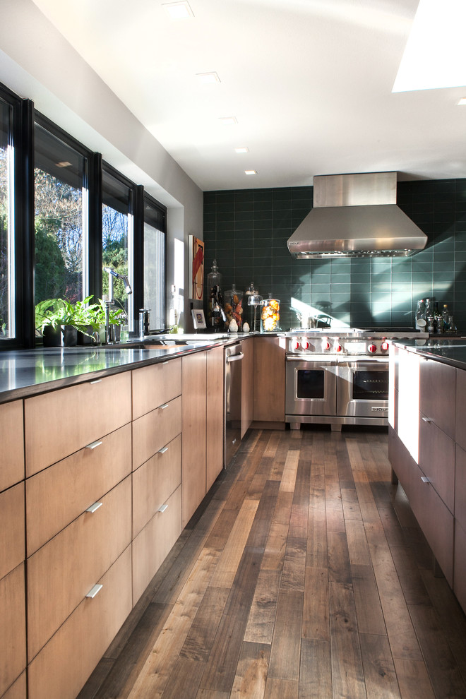 Photo of a large midcentury u-shaped eat-in kitchen in Portland with an undermount sink, flat-panel cabinets, medium wood cabinets, granite benchtops, green splashback, ceramic splashback, stainless steel appliances, dark hardwood floors and with island.