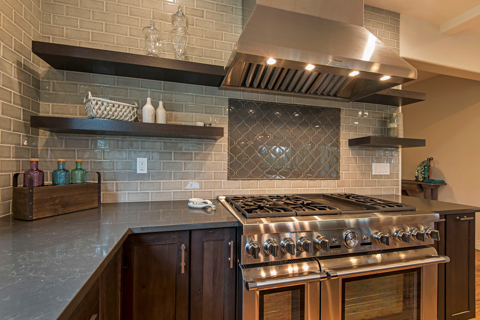 Open concept kitchen - large transitional l-shaped medium tone wood floor and brown floor open concept kitchen idea with a farmhouse sink, shaker cabinets, dark wood cabinets, granite countertops, gray backsplash, subway tile backsplash, paneled appliances and an island