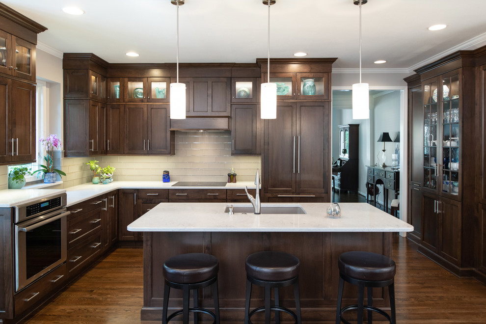 Photo of a mid-sized contemporary l-shaped open plan kitchen in Kansas City with shaker cabinets, dark wood cabinets, quartz benchtops, glass tile splashback, dark hardwood floors and with island.