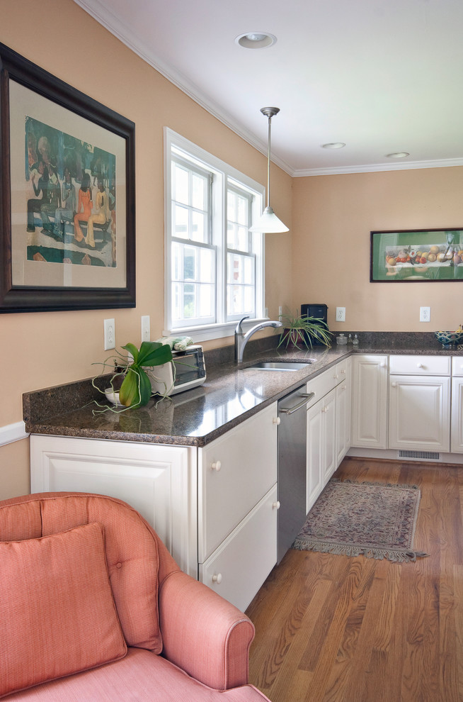 Mid-sized traditional l-shaped kitchen in Charleston with a double-bowl sink, raised-panel cabinets, white cabinets, granite benchtops, medium hardwood floors, with island and brown floor.