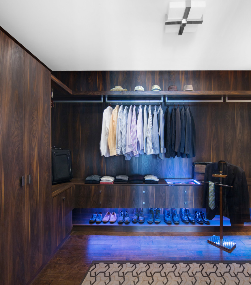 Large modern men's walk-in wardrobe in San Francisco with flat-panel cabinets, dark wood cabinets, dark hardwood floors and brown floor.