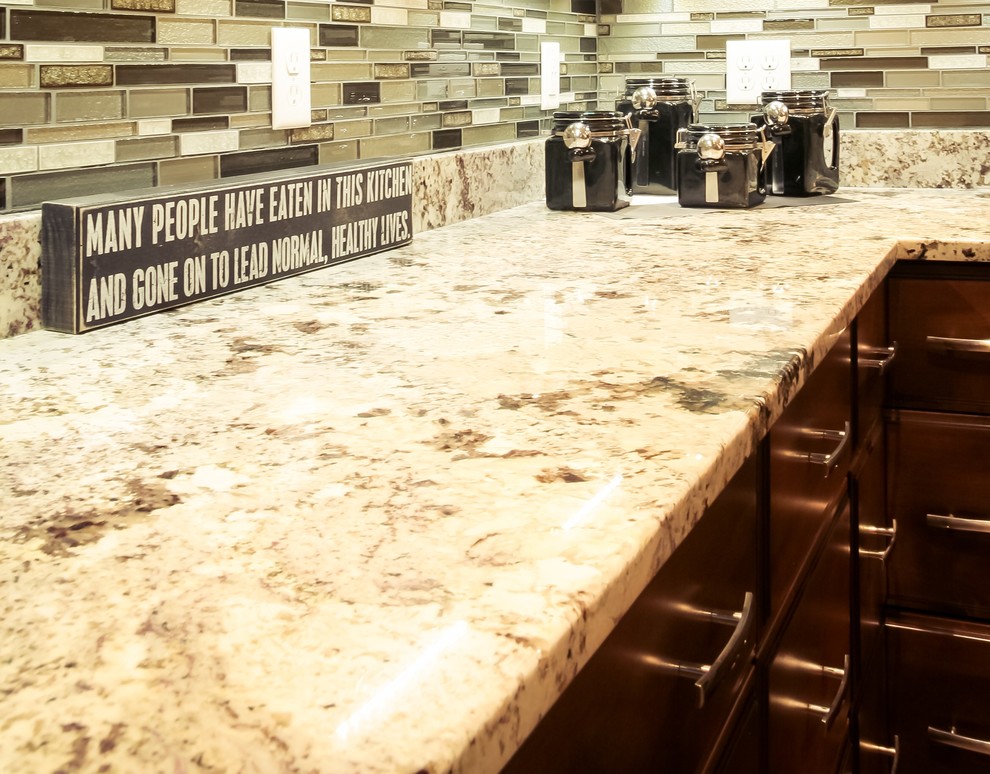 Inspiration for a large transitional l-shaped medium tone wood floor home design remodel with an undermount sink, raised-panel cabinets, medium tone wood cabinets, granite countertops, glass tile backsplash, stainless steel appliances and an island