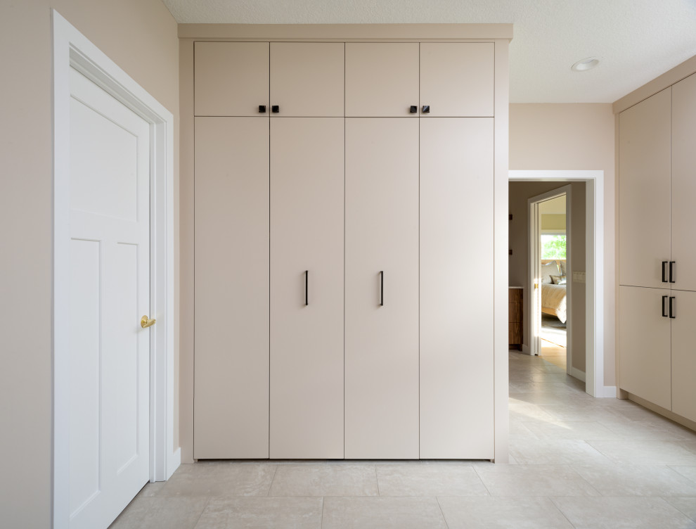 Medium sized contemporary single-wall laundry cupboard in Minneapolis with flat-panel cabinets, a concealed washer and dryer, beige cabinets, ceramic flooring and beige floors.