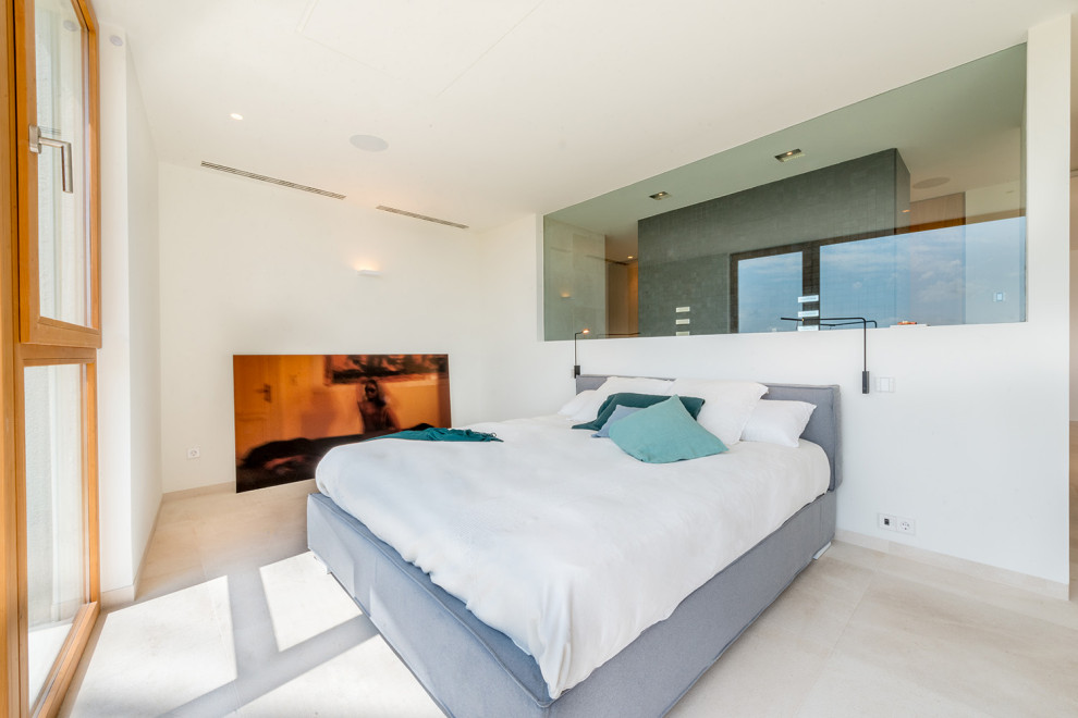 Large mediterranean master bedroom in Palma de Mallorca with beige walls and beige floor.
