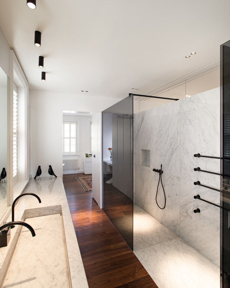 This is an example of a contemporary master bathroom in London with a curbless shower, black and white tile, marble, white walls, dark hardwood floors, an integrated sink, marble benchtops, brown floor and an open shower.