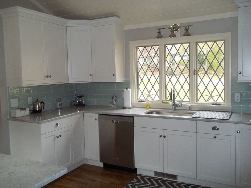 This is an example of a mid-sized traditional l-shaped kitchen in Boston with a drop-in sink, recessed-panel cabinets, white cabinets, blue splashback, stainless steel appliances, medium hardwood floors and with island.