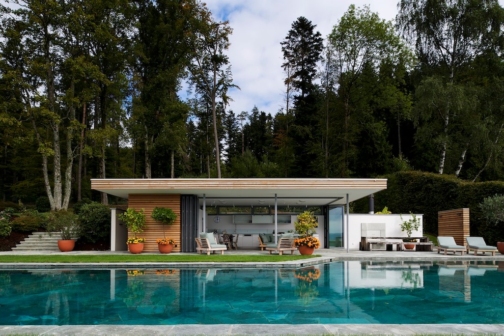 Contemporary backyard custom-shaped pool in Other with a pool house.