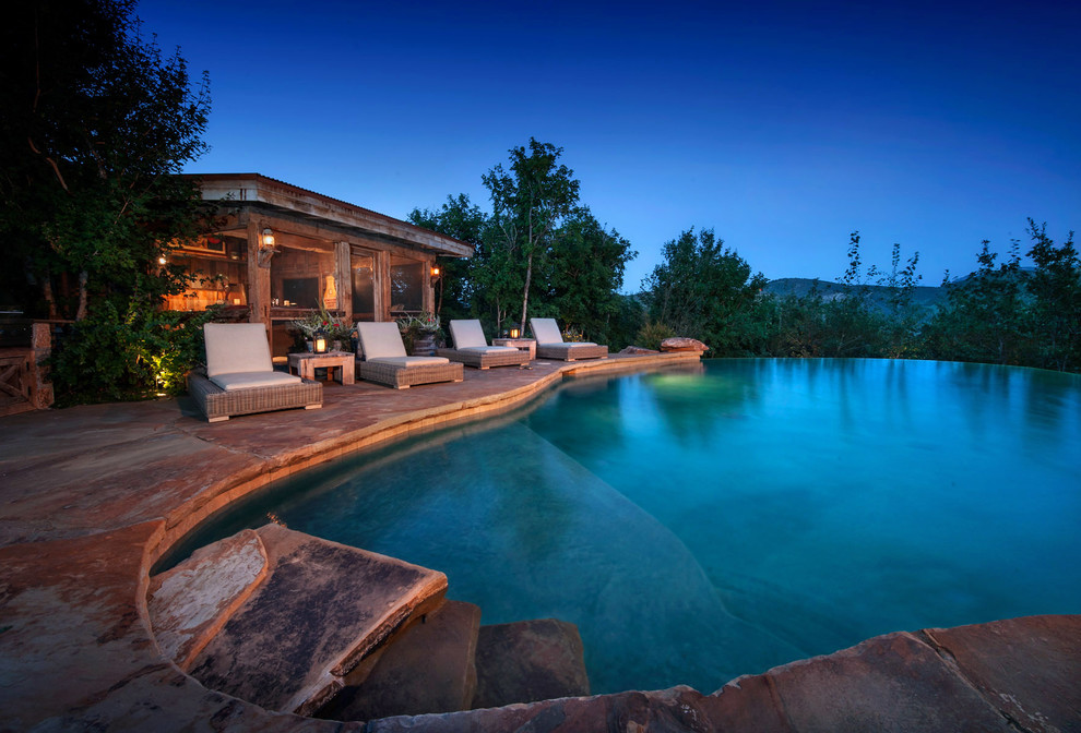 This is an example of a country backyard custom-shaped infinity pool in Salt Lake City with a pool house.