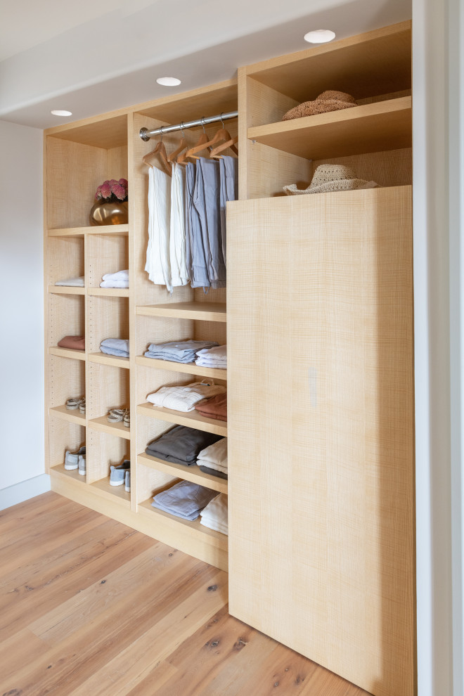 Diseño de armario vestidor escandinavo grande con armarios con paneles lisos, puertas de armario de madera clara, suelo de baldosas de porcelana y suelo gris