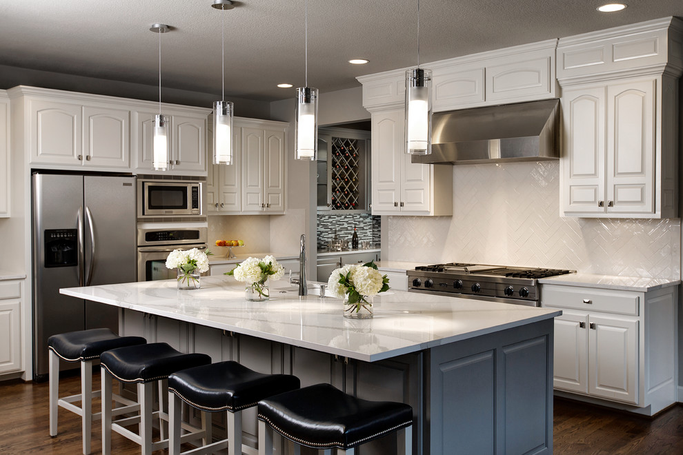 Photo of a large transitional l-shaped eat-in kitchen in Kansas City with an undermount sink, raised-panel cabinets, white cabinets, quartz benchtops, white splashback, subway tile splashback, stainless steel appliances, dark hardwood floors and with island.