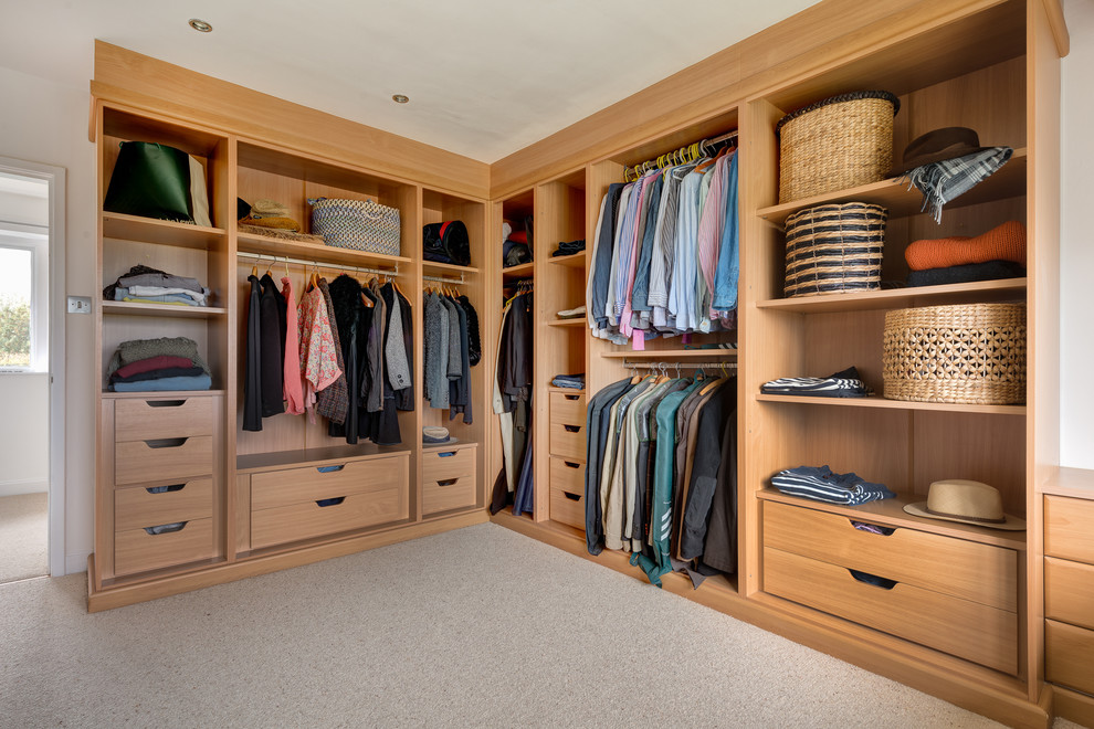 Design ideas for a mid-sized contemporary gender-neutral walk-in wardrobe in Devon with flat-panel cabinets, light wood cabinets and carpet.