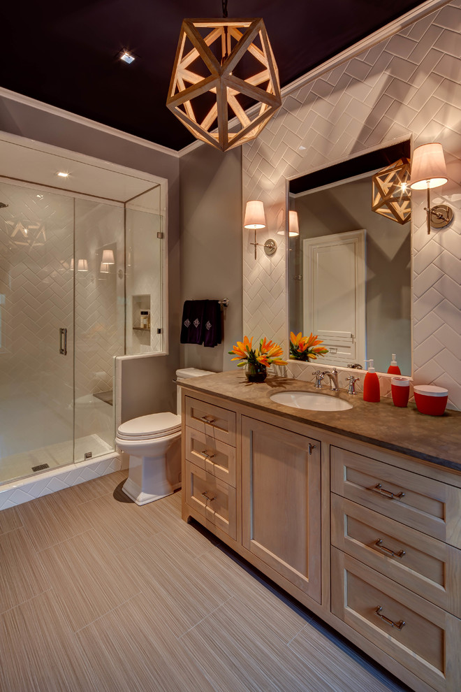 Photo of a traditional bathroom in Houston with furniture-like cabinets, dark wood cabinets, brown walls, an undermount sink, beige floor, an alcove shower, a one-piece toilet, gray tile, subway tile and a hinged shower door.