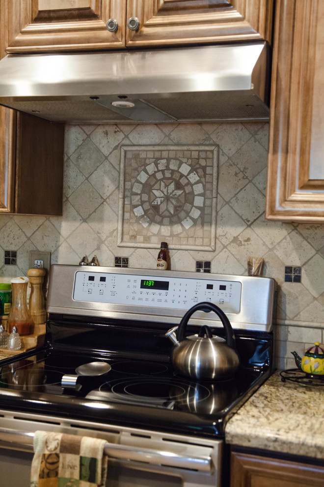 Mid-sized transitional l-shaped travertine floor eat-in kitchen photo in Phoenix with an undermount sink, raised-panel cabinets, medium tone wood cabinets, granite countertops, beige backsplash, stone tile backsplash, stainless steel appliances and an island