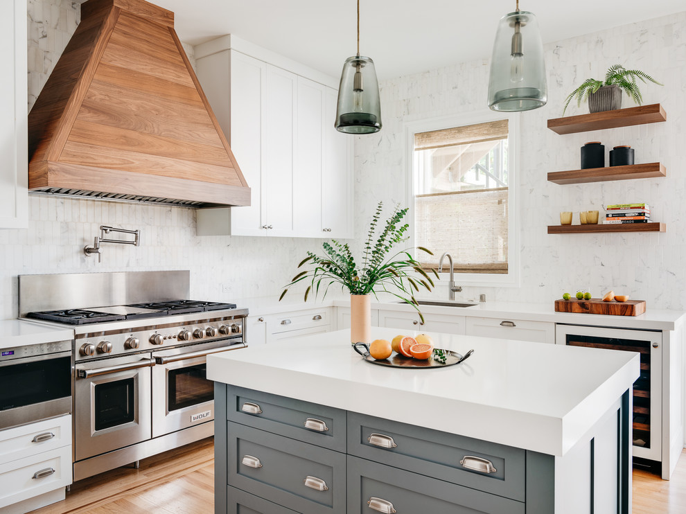 Inspiration for a mid-sized transitional u-shaped kitchen in San Francisco with an undermount sink, shaker cabinets, white cabinets, white splashback, stainless steel appliances, light hardwood floors, with island, white benchtop, quartz benchtops, marble splashback and beige floor.