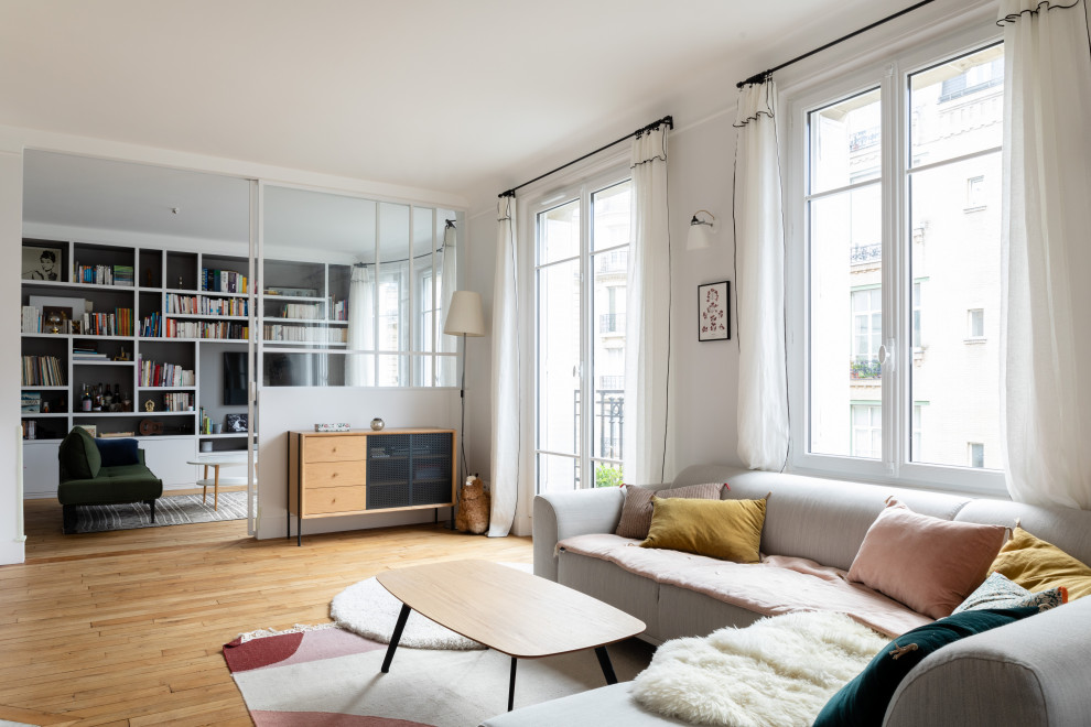 Photo of a mid-sized scandinavian open concept living room in Paris with a library, white walls, light hardwood floors, no fireplace, a built-in media wall and beige floor.