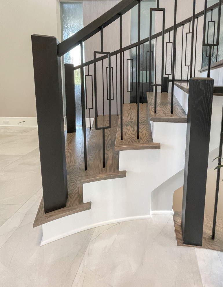 Стильный дизайн: огромная изогнутая лестница в стиле неоклассика (современная классика) с деревянными ступенями, крашенными деревянными подступенками, перилами из смешанных материалов и обоями на стенах - последний тренд