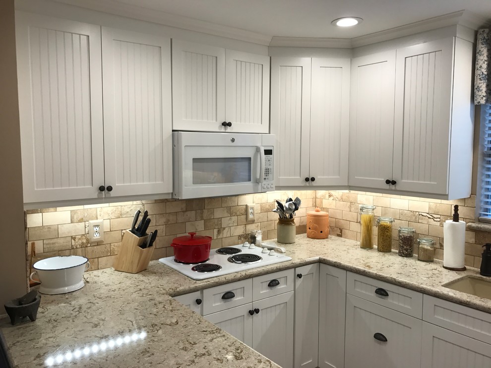 Small traditional u-shaped separate kitchen in Houston with an undermount sink, louvered cabinets, white cabinets, laminate benchtops, beige splashback, stone tile splashback, white appliances and a peninsula.