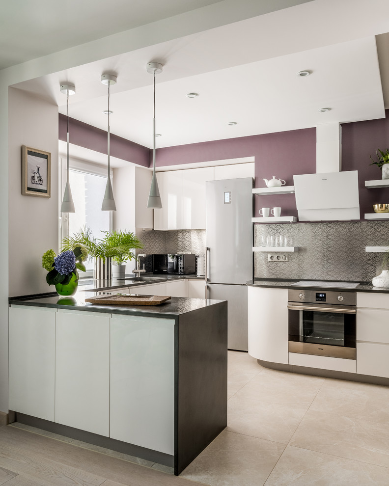 Photo of a contemporary u-shaped kitchen in Moscow with flat-panel cabinets, white cabinets, metallic splashback, metal splashback, stainless steel appliances, a peninsula, beige floor and black benchtop.