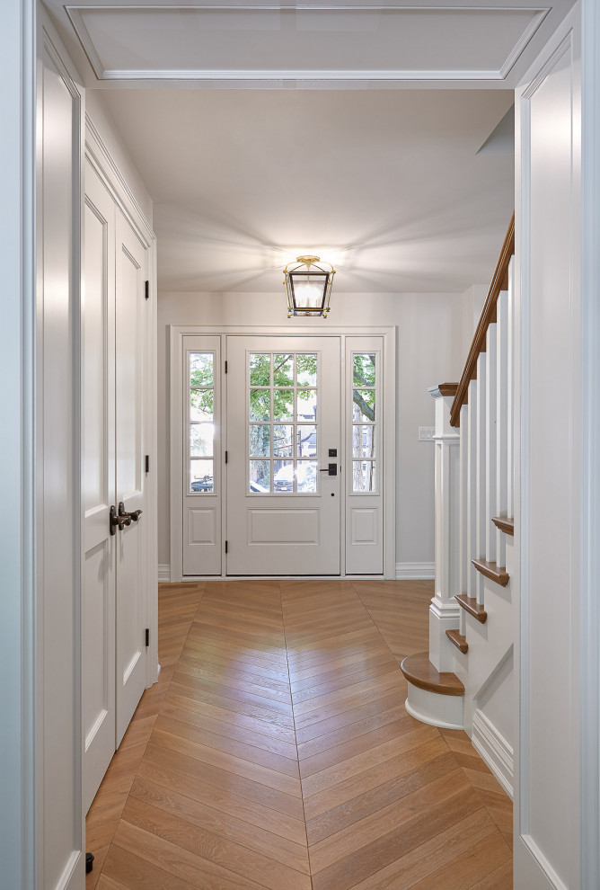 Mid-sized transitional light wood floor entry hall photo in Toronto with white walls and a white front door