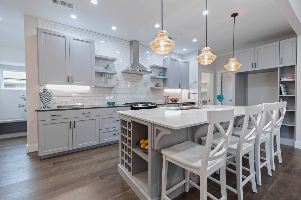 Example of a mid-sized transitional galley medium tone wood floor open concept kitchen design in Dallas with a double-bowl sink, shaker cabinets, gray cabinets, quartz countertops, white backsplash, subway tile backsplash, stainless steel appliances and an island