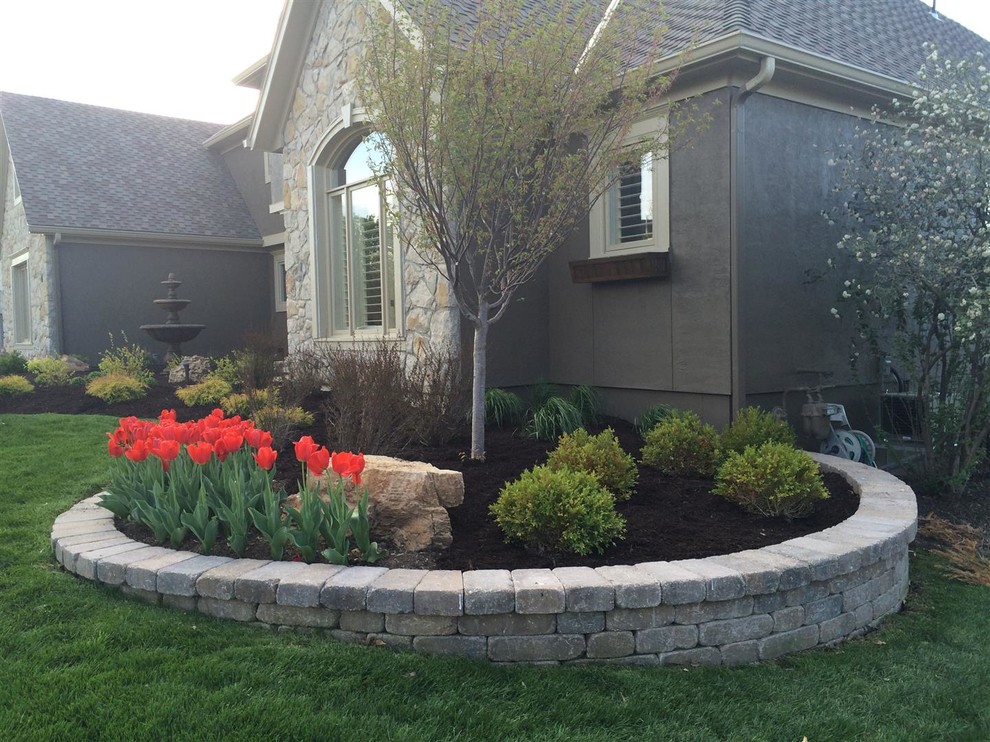 Photo of a large traditional front yard full sun garden for spring in Kansas City with a retaining wall and mulch.