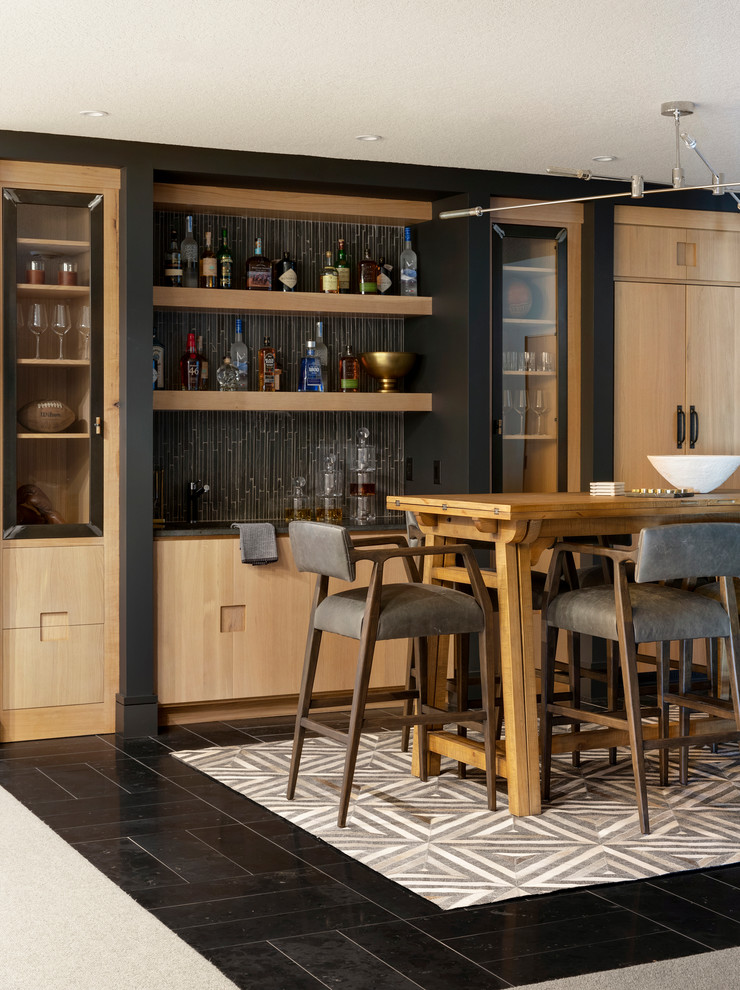 Photo of a contemporary seated home bar in Minneapolis with light wood cabinets, wood benchtops, black splashback, mosaic tile splashback, black floor and brown benchtop.