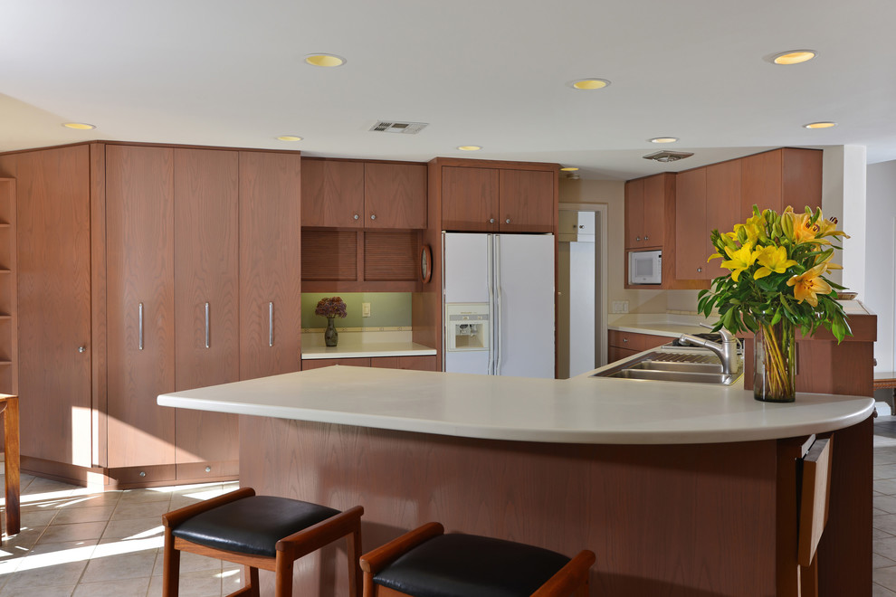 Photo of a midcentury l-shaped eat-in kitchen in San Diego with a double-bowl sink, flat-panel cabinets, medium wood cabinets and white appliances.
