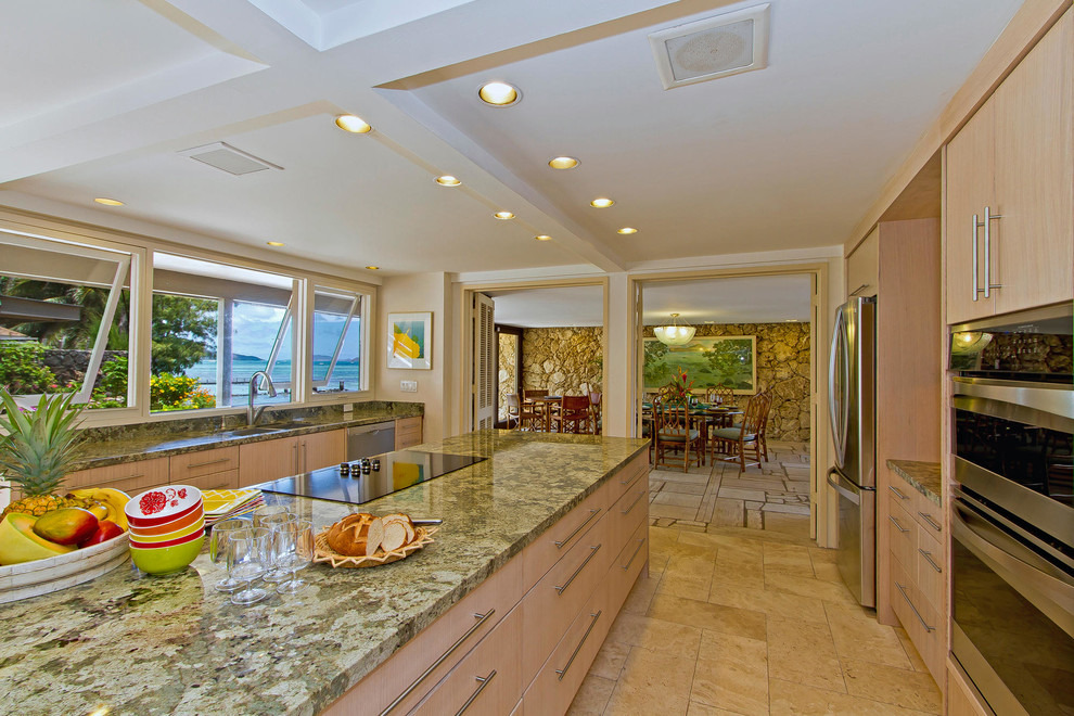 Large modern galley separate kitchen in Hawaii with a double-bowl sink, flat-panel cabinets, light wood cabinets, granite benchtops, stainless steel appliances, travertine floors, with island, brown floor and green benchtop.
