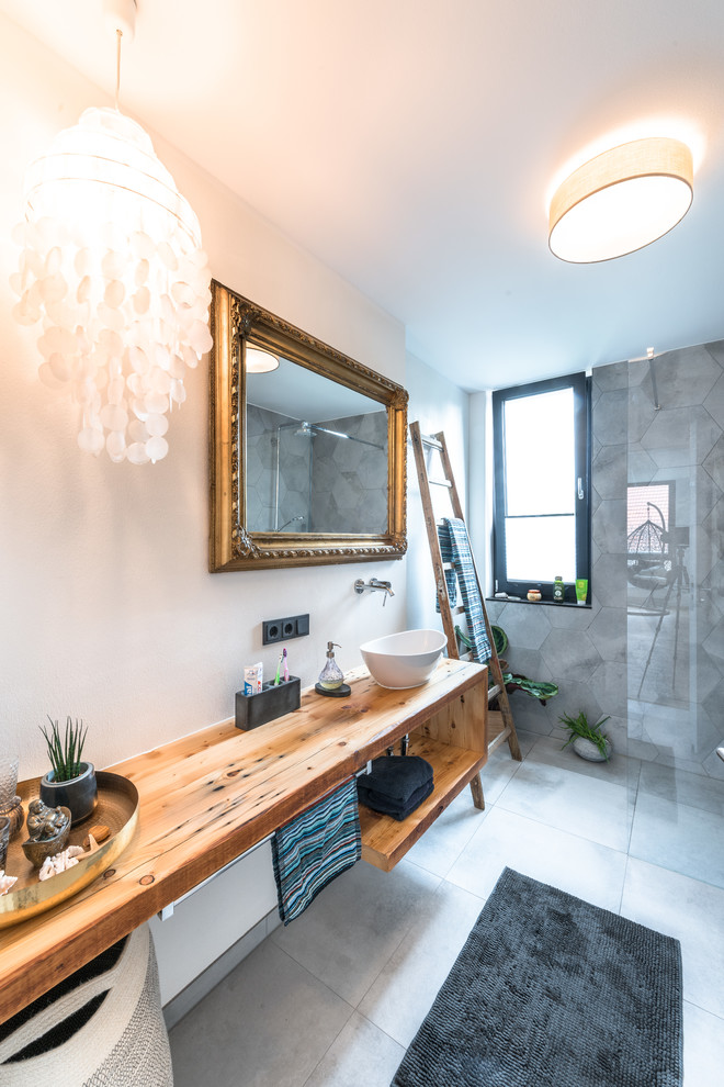 Mid-sized scandinavian 3/4 bathroom in Cologne with a curbless shower, gray tile, cement tile, cement tiles, a vessel sink, wood benchtops, grey floor, an open shower, brown benchtops, open cabinets, white walls and medium wood cabinets.