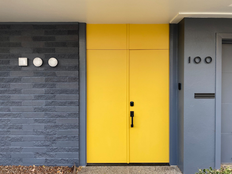 Aménagement d'une porte d'entrée rétro avec un mur gris, une porte jaune et une porte double.