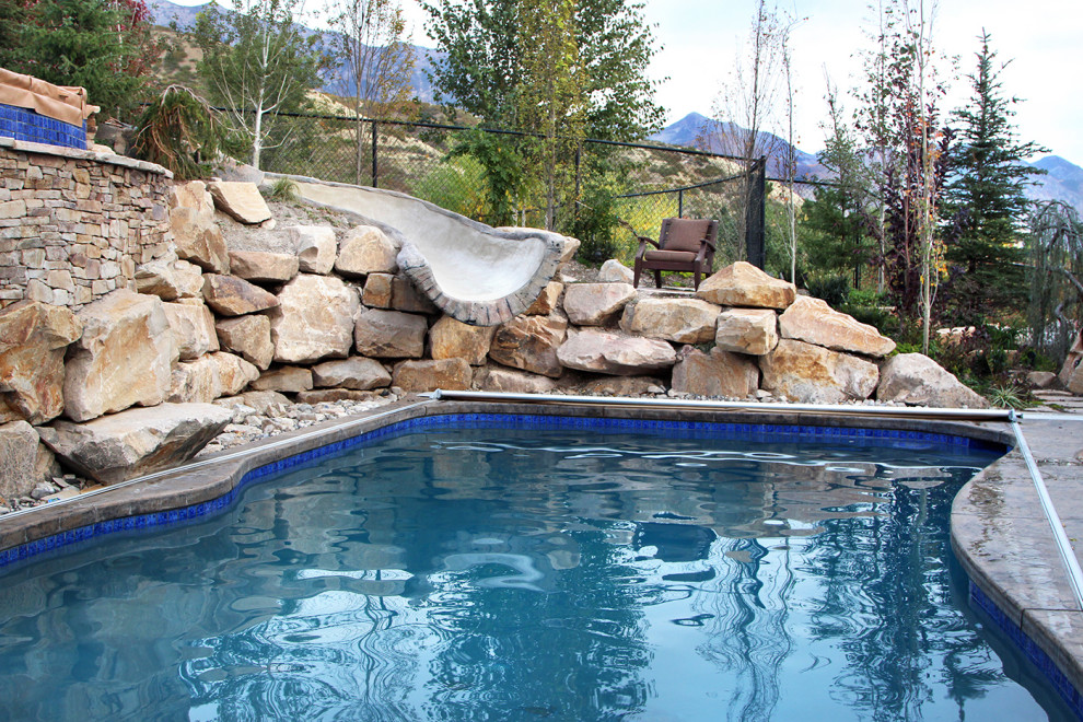 Foto de piscina con tobogán rural a medida en patio trasero con adoquines de piedra natural