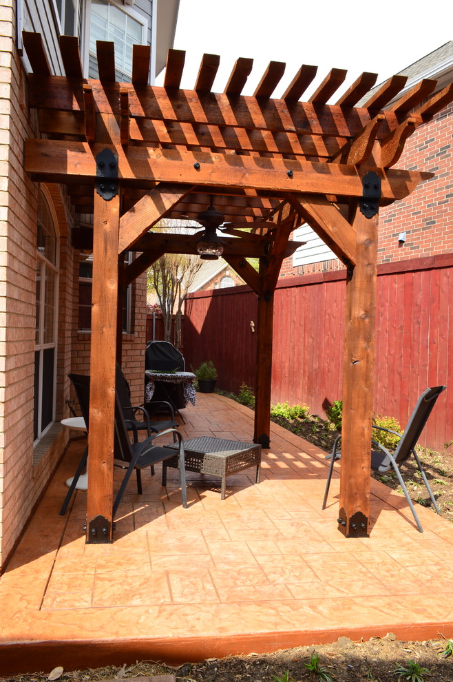 Design ideas for a mid-sized country side yard patio in Dallas with stamped concrete and a pergola.