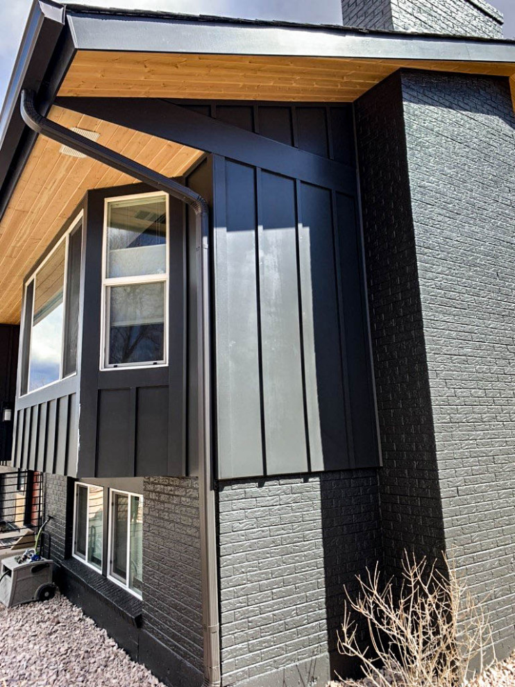 Imagen de fachada de casa negra minimalista con panel y listón