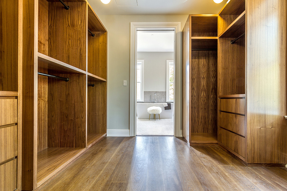 Inspiration for a transitional master and gender-neutral medium tone wood floor and brown floor walk-in closet remodel in New York with flat-panel cabinets and medium tone wood cabinets