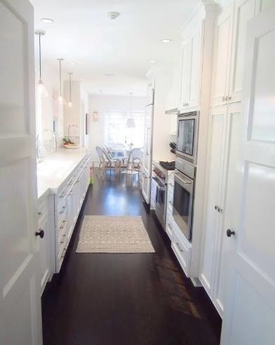Design ideas for a mid-sized traditional galley eat-in kitchen in Los Angeles with white cabinets, multi-coloured splashback, stainless steel appliances, dark hardwood floors, no island, raised-panel cabinets, brown floor and white benchtop.