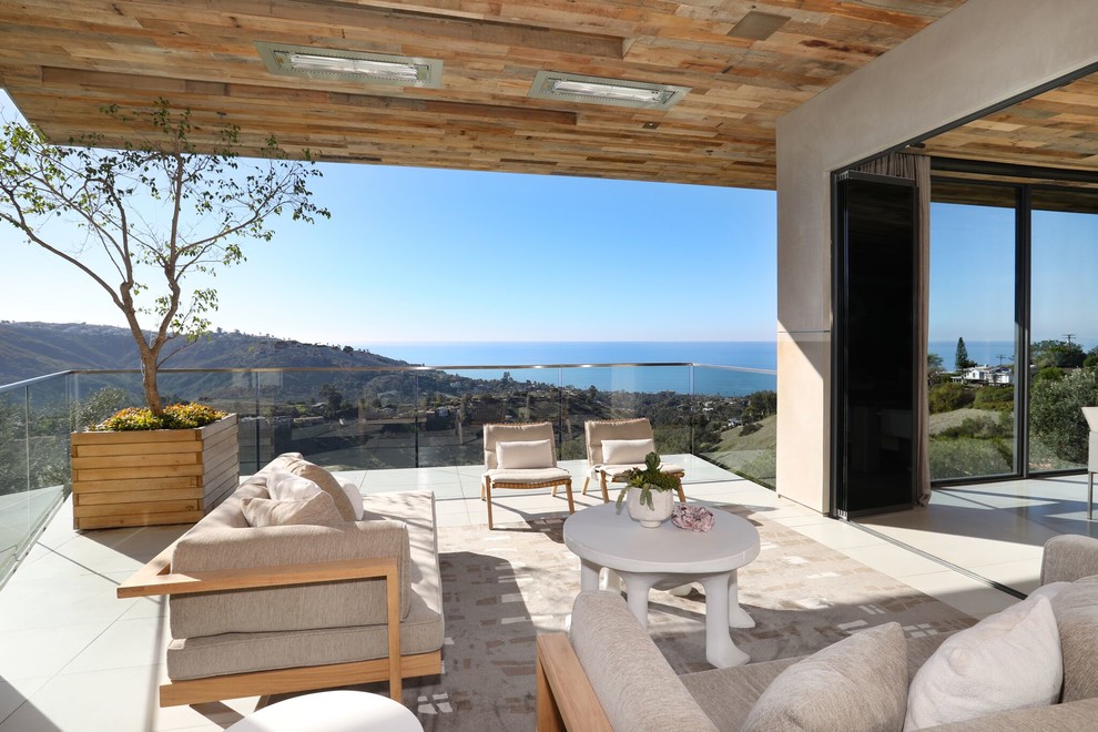 Inspiration for a large contemporary backyard concrete deck remodel in Orange County with a fireplace and a roof extension