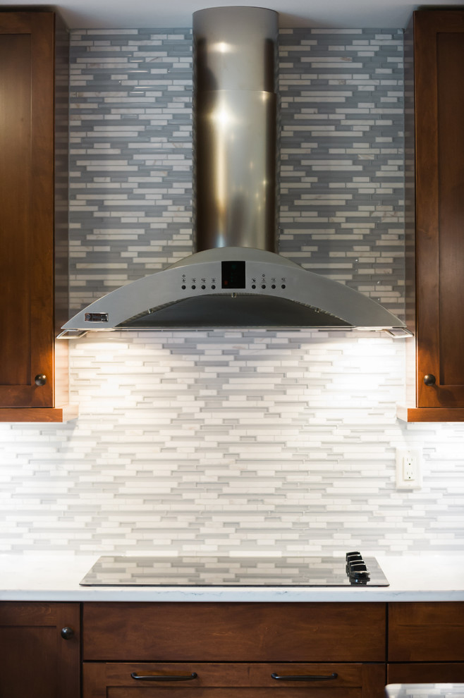 Example of a large transitional l-shaped light wood floor eat-in kitchen design with an undermount sink, shaker cabinets, dark wood cabinets, quartz countertops, gray backsplash, matchstick tile backsplash, stainless steel appliances and an island