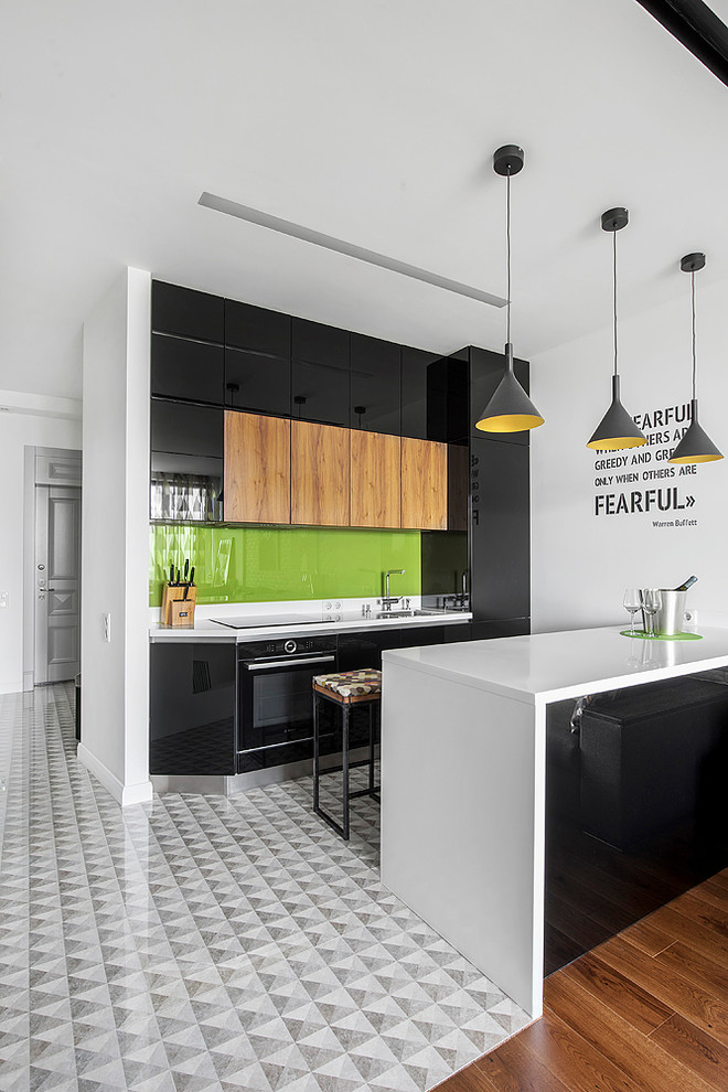 Photo of a mid-sized contemporary galley open plan kitchen in Moscow with an undermount sink, flat-panel cabinets, black cabinets, solid surface benchtops, green splashback, glass sheet splashback, porcelain floors, a peninsula, grey floor and black appliances.
