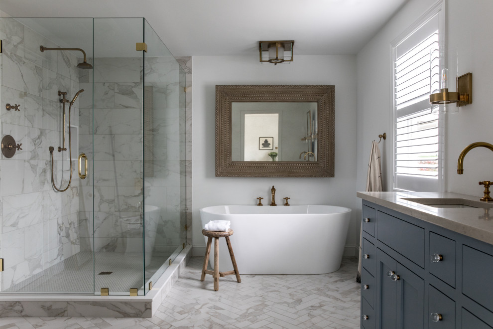 Inspiration for a transitional bathroom in Boston with shaker cabinets, blue cabinets, a freestanding tub, white walls, an undermount sink, grey floor, beige benchtops, a niche, a double vanity and a built-in vanity.