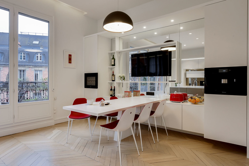 Inspiration for an expansive contemporary open plan kitchen in Paris with an undermount sink, flat-panel cabinets, white cabinets, mirror splashback, panelled appliances, light hardwood floors, with island and beige floor.