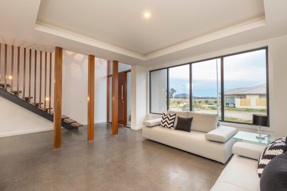 This is an example of a contemporary formal open concept living room in Canberra - Queanbeyan with white walls, concrete floors and no tv.