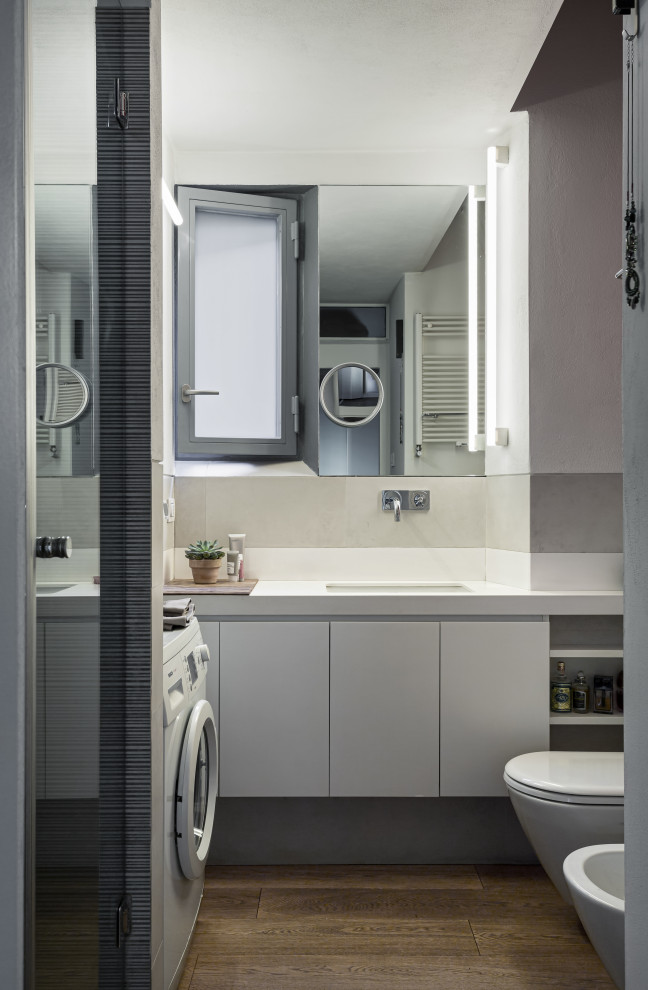 Пример оригинального дизайна: маленькая главная ванная комната со стиральной машиной в современном стиле с плоскими фасадами, белыми фасадами, душем в нише, раздельным унитазом, белой плиткой, керамогранитной плиткой, белыми стенами, паркетным полом среднего тона, врезной раковиной, столешницей из искусственного камня, бежевым полом, душем с распашными дверями, белой столешницей, тумбой под одну раковину, подвесной тумбой и многоуровневым потолком для на участке и в саду