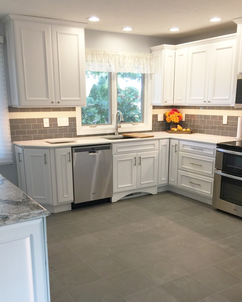Photo of a mid-sized traditional u-shaped separate kitchen in Chicago with an undermount sink, flat-panel cabinets, white cabinets, quartz benchtops, grey splashback, glass tile splashback, stainless steel appliances, porcelain floors, with island and grey floor.