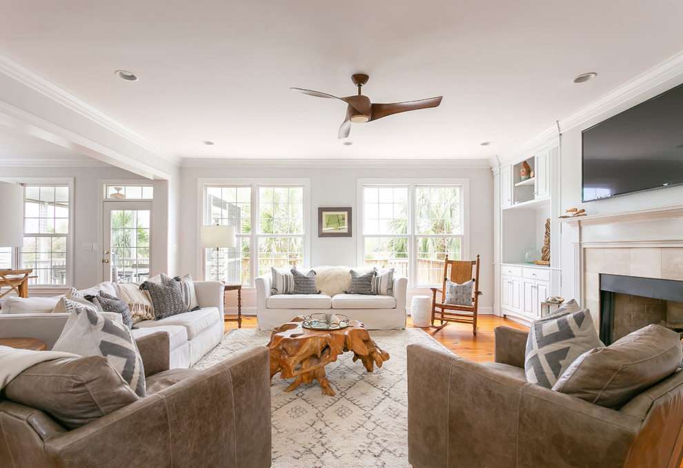 Inspiration for a large beach style open concept living room in Charleston with white walls, light hardwood floors, a standard fireplace, a tile fireplace surround, a wall-mounted tv and brown floor.