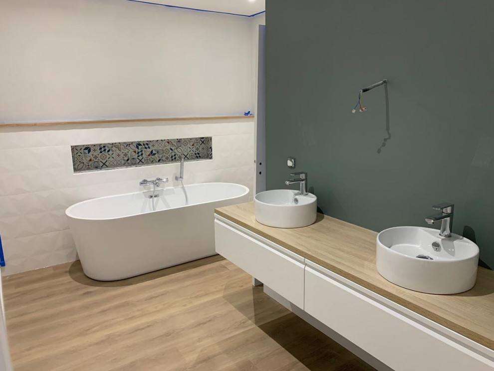 Cette image montre une salle de bain minimaliste de taille moyenne pour enfant avec une baignoire indépendante, un lavabo suspendu et meuble double vasque.