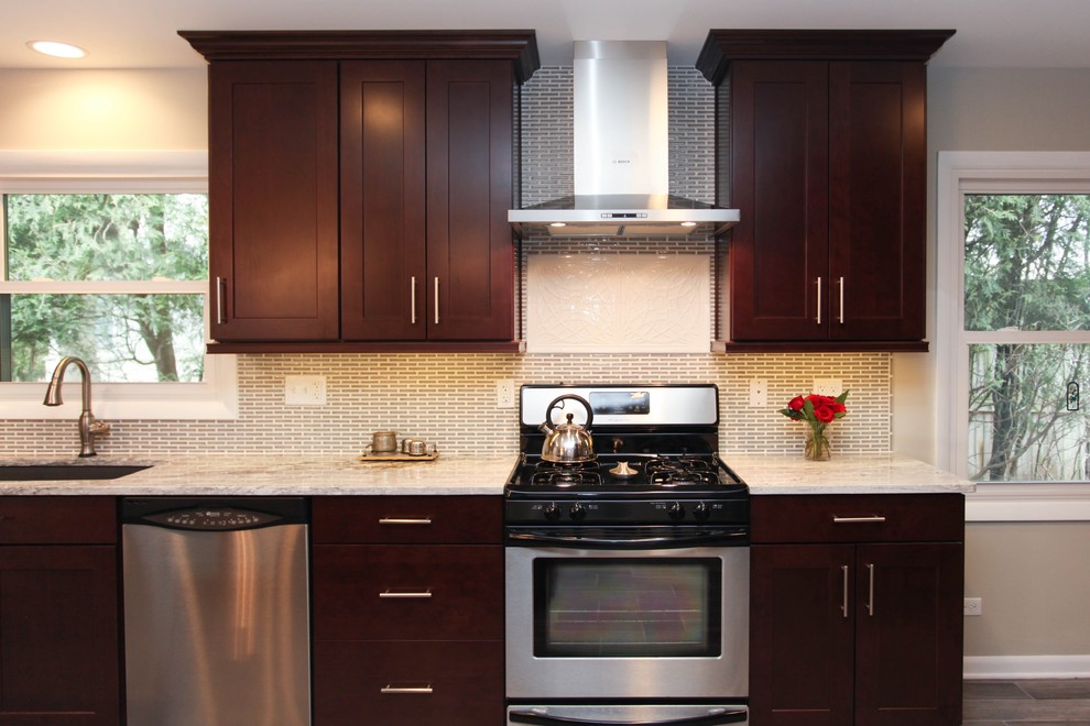 Eat-in kitchen - large transitional u-shaped porcelain tile eat-in kitchen idea in Chicago with an undermount sink, recessed-panel cabinets, dark wood cabinets, granite countertops, gray backsplash, glass tile backsplash, stainless steel appliances and an island
