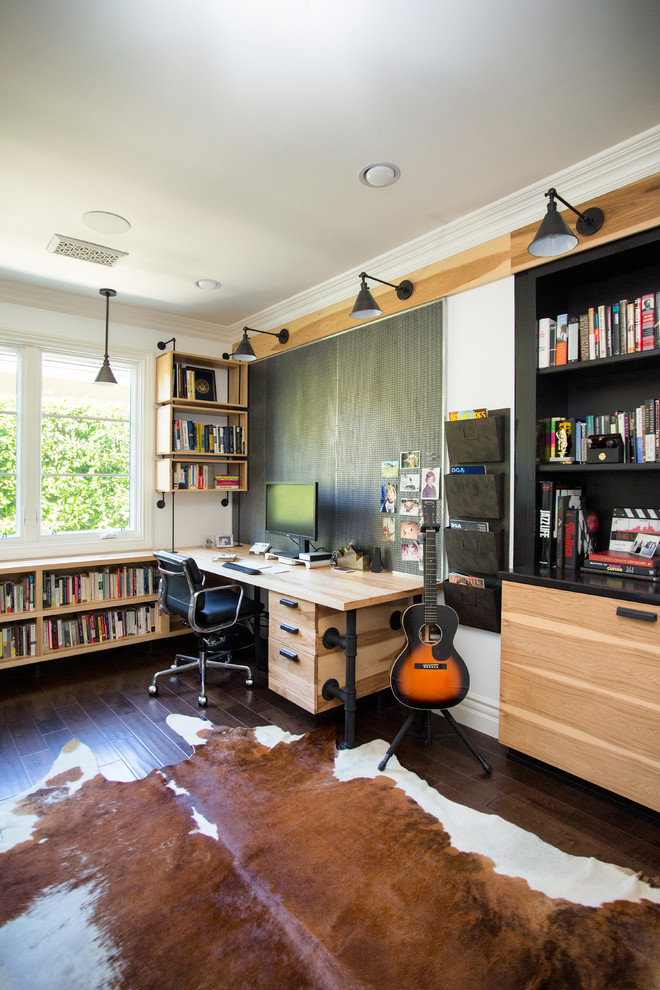 Contemporary home studio in Los Angeles with white walls, dark hardwood floors, a built-in desk and brown floor.