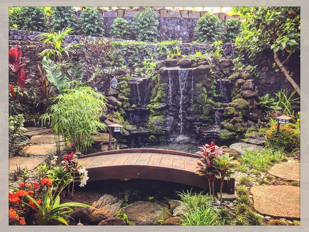 Photo of a large tropical courtyard full sun formal garden in Other with with waterfall and natural stone pavers.